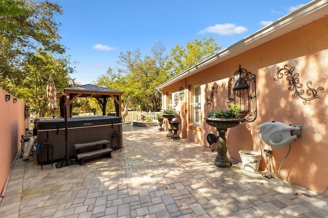 view of patio / terrace with a gazebo, fence, and a hot tub