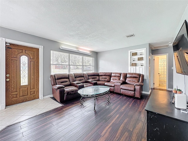 living area with visible vents, plenty of natural light, and wood finished floors