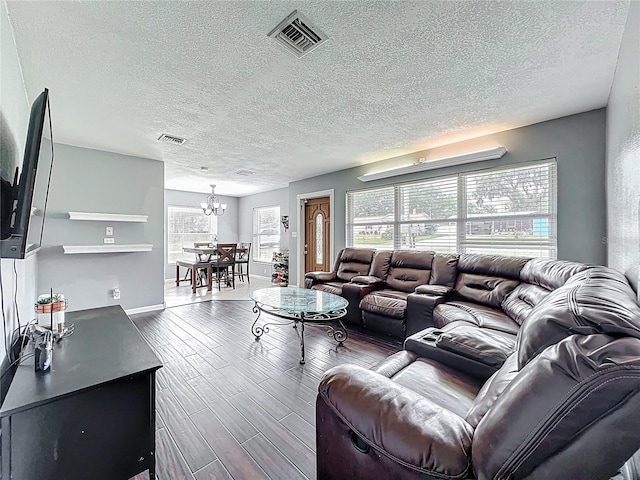 living room featuring an inviting chandelier, wood finished floors, visible vents, and a textured ceiling