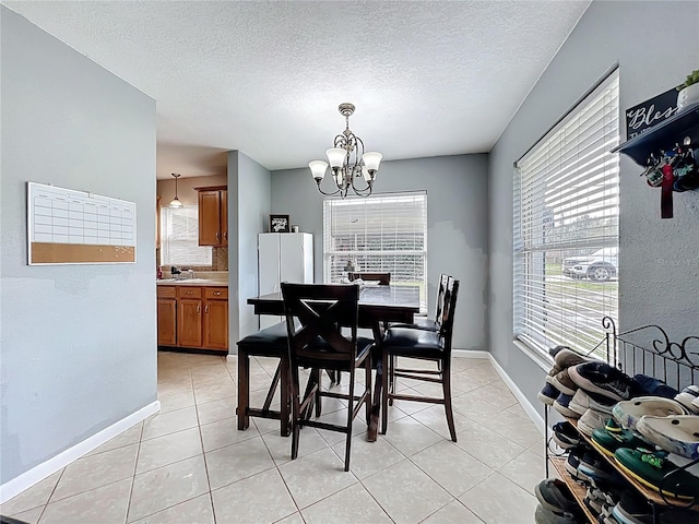 dining room with a chandelier, light tile patterned floors, a textured ceiling, and baseboards