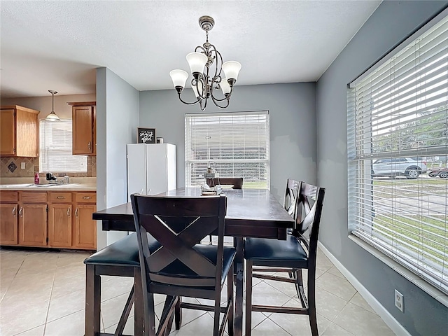 dining area with a chandelier, light tile patterned floors, a healthy amount of sunlight, and baseboards