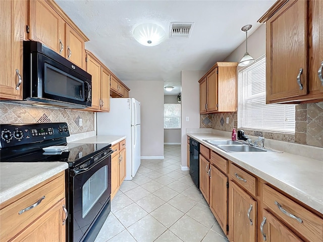 kitchen featuring light tile patterned floors, visible vents, a sink, black appliances, and light countertops