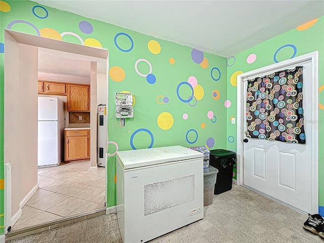 clothes washing area featuring baseboards and water heater