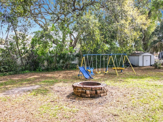 view of yard with an outbuilding, a playground, a storage unit, and a fire pit