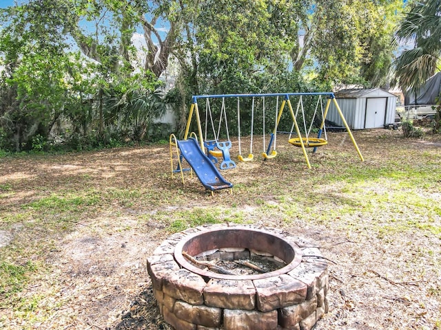 view of yard featuring an outbuilding, a shed, a fire pit, and a playground