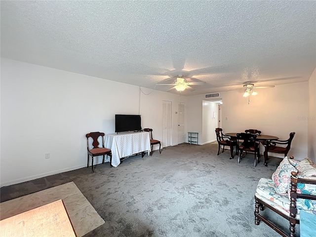 living room with visible vents, a textured ceiling, ceiling fan, and carpet flooring