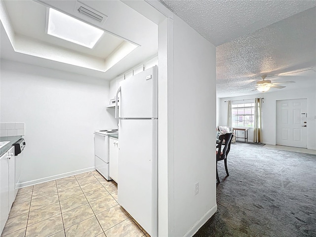 kitchen with visible vents, a textured ceiling, light carpet, white appliances, and white cabinetry