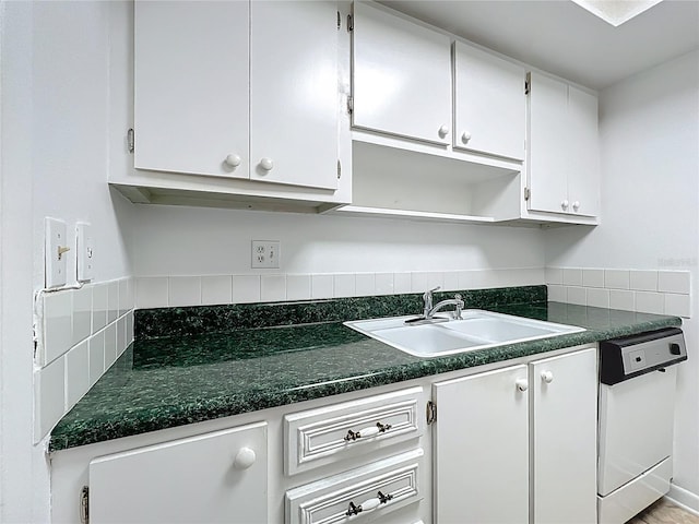 kitchen featuring white cabinetry, dark countertops, white dishwasher, and a sink