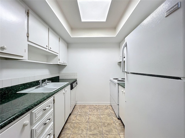 kitchen with white appliances, a sink, white cabinetry, dark countertops, and a raised ceiling