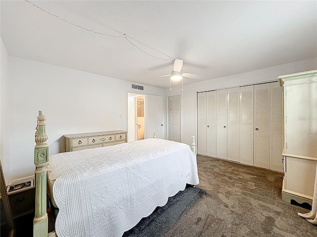 carpeted bedroom featuring visible vents, two closets, and a ceiling fan