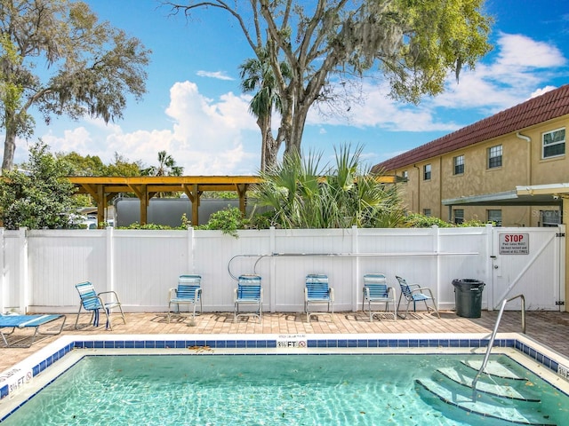 community pool with a patio area and fence