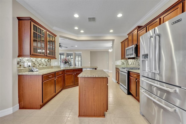 kitchen featuring visible vents, a center island, glass insert cabinets, a peninsula, and stainless steel appliances