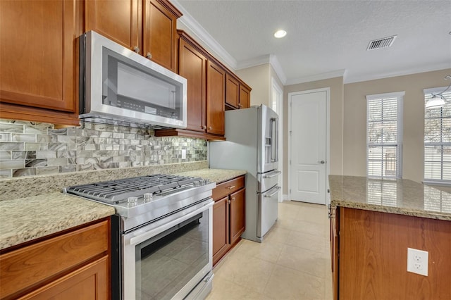 kitchen with visible vents, brown cabinets, ornamental molding, light stone counters, and appliances with stainless steel finishes