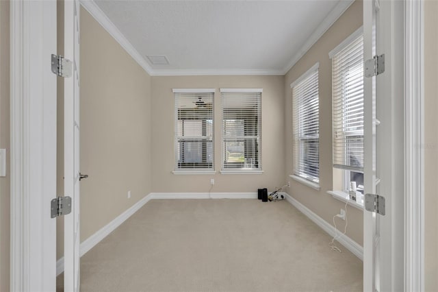 empty room featuring crown molding, baseboards, and light carpet