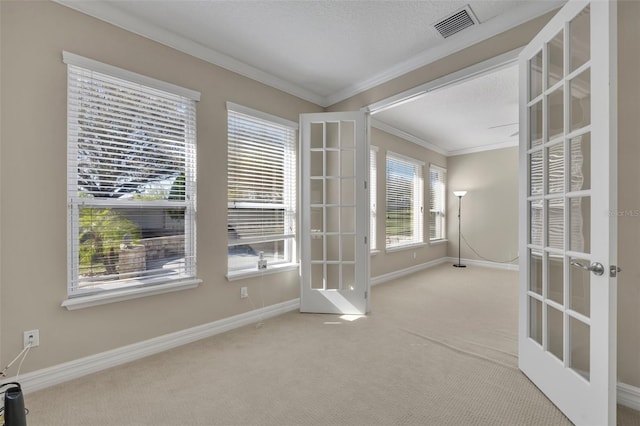 carpeted spare room with visible vents, french doors, baseboards, and ornamental molding