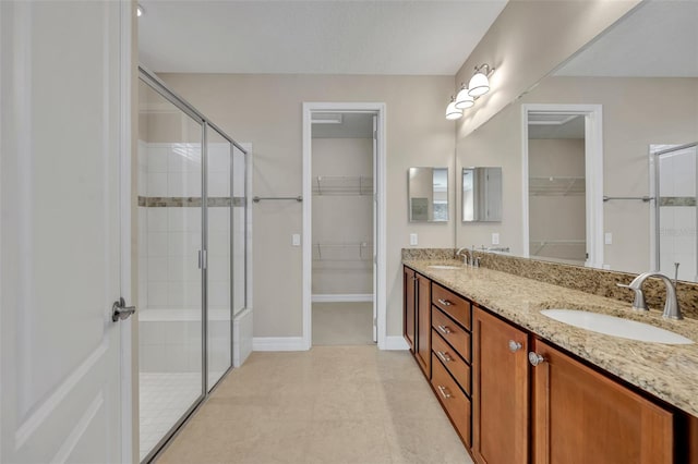 bathroom featuring a shower stall, a spacious closet, double vanity, and a sink