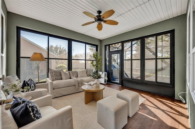 living area featuring wood finished floors, ceiling fan, and a textured wall