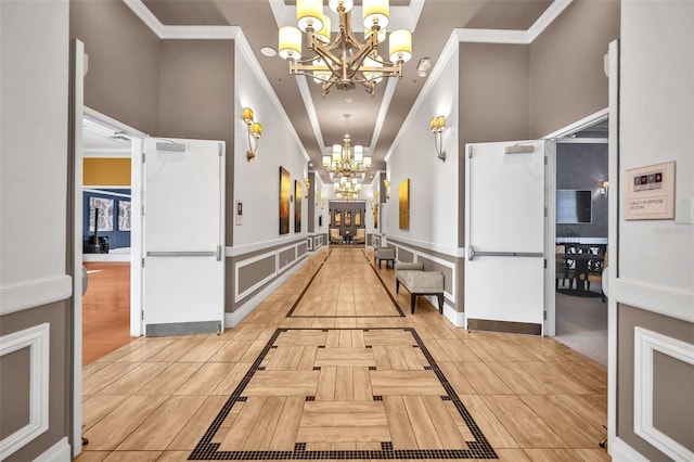 hall with light tile patterned flooring, a notable chandelier, crown molding, and baseboards