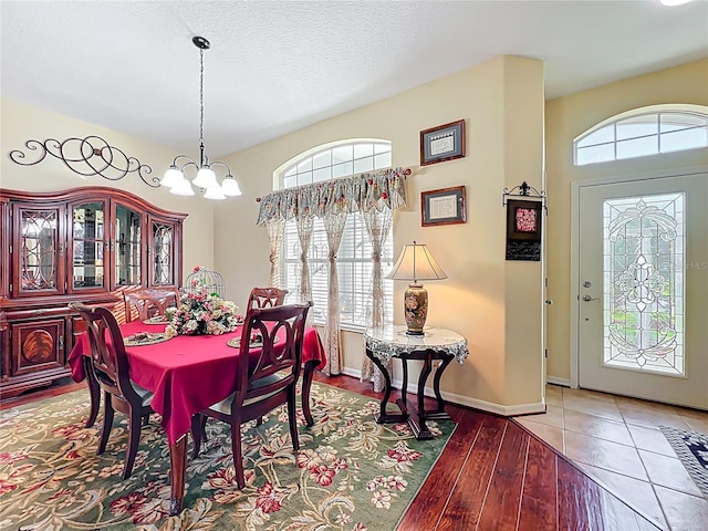 dining room featuring light wood-style flooring, a healthy amount of sunlight, baseboards, and a chandelier