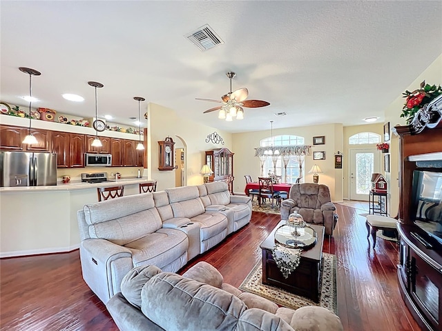 living area featuring dark wood-style floors, visible vents, a textured ceiling, and ceiling fan