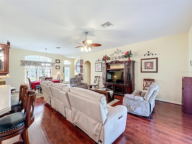 living area featuring visible vents, arched walkways, dark wood-style floors, and ceiling fan with notable chandelier