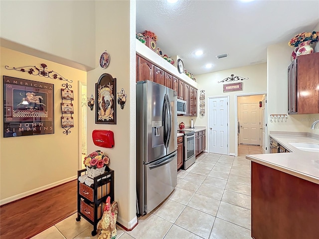 kitchen featuring light tile patterned floors, visible vents, a sink, light countertops, and appliances with stainless steel finishes