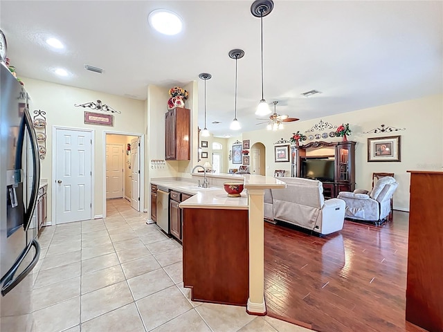 kitchen with visible vents, refrigerator with ice dispenser, arched walkways, a peninsula, and light countertops