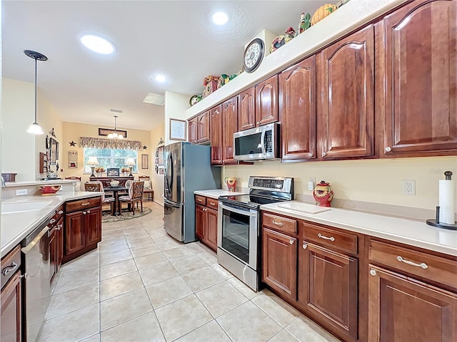 kitchen with a sink, light countertops, appliances with stainless steel finishes, and pendant lighting