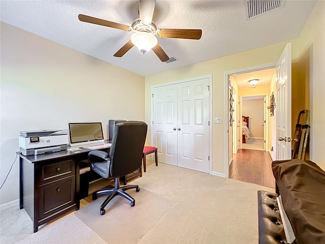 home office featuring baseboards, light colored carpet, visible vents, and a textured ceiling