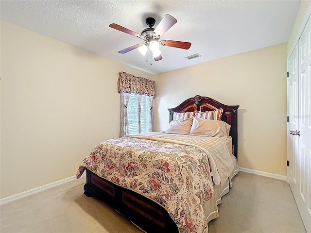 bedroom featuring visible vents, a textured ceiling, a closet, baseboards, and ceiling fan