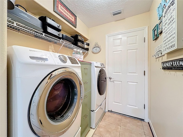 washroom with visible vents, independent washer and dryer, a textured ceiling, light tile patterned floors, and laundry area