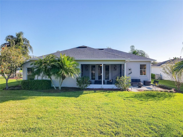 back of property with roof with shingles, stucco siding, a yard, a sunroom, and a patio area