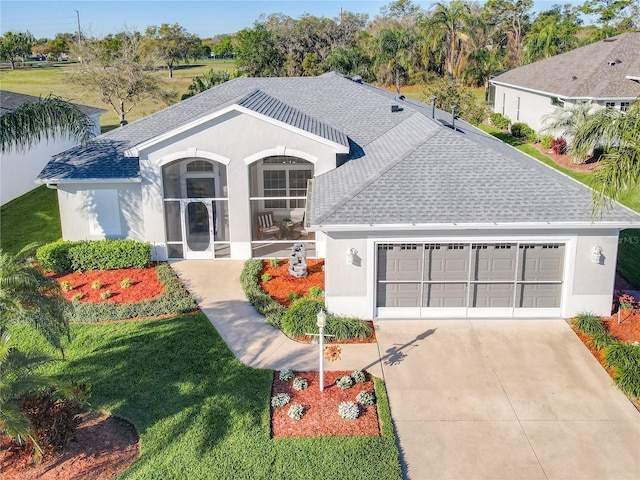 27023 Old English Ct, Leesburg, FL 34748 - view of front facade featuring roof with shingles, a garage, driveway, stucco siding, and a front lawn