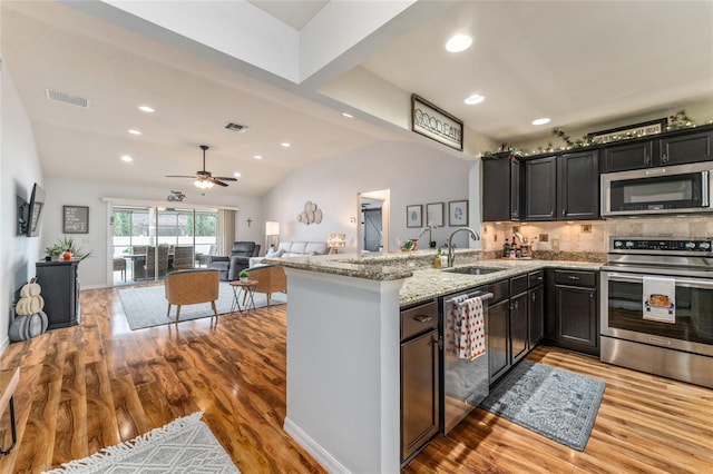 kitchen featuring a sink, stainless steel appliances, light stone counters, and visible vents