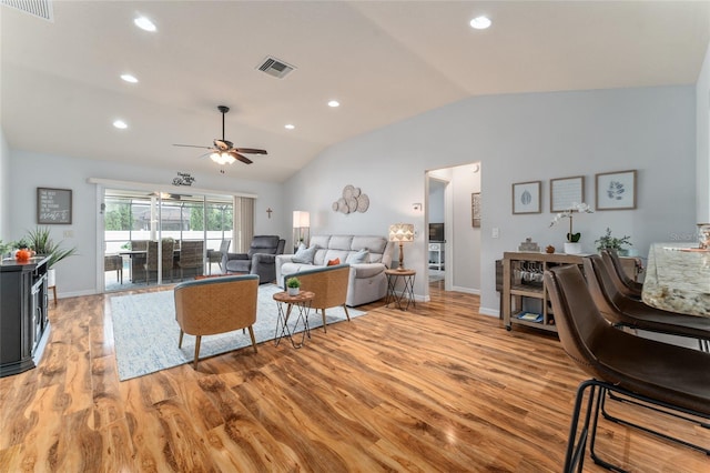 living area featuring visible vents, light wood-style floors, and vaulted ceiling