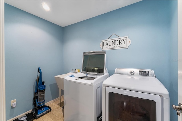 clothes washing area with tile patterned floors, baseboards, separate washer and dryer, and laundry area