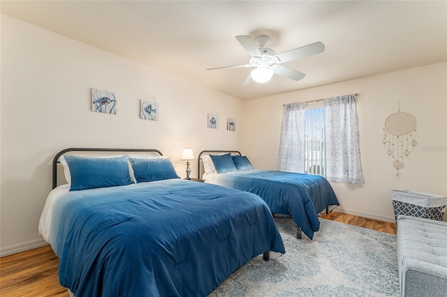 bedroom with a ceiling fan, baseboards, and wood finished floors