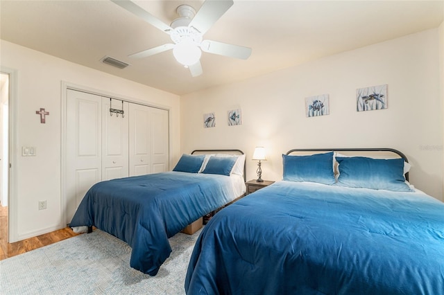 bedroom with visible vents, wood finished floors, a closet, baseboards, and ceiling fan