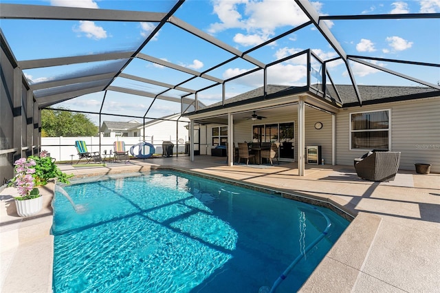 view of swimming pool featuring fence, glass enclosure, a fenced in pool, ceiling fan, and a patio area