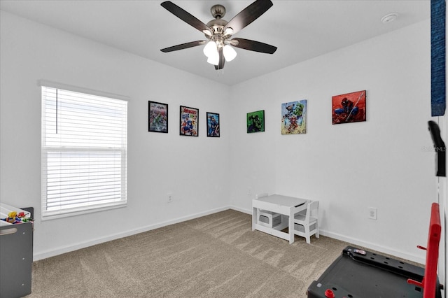 exercise area with baseboards, a ceiling fan, and carpet flooring