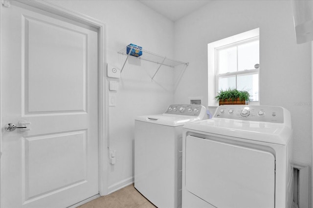 clothes washing area featuring light tile patterned floors, baseboards, washing machine and dryer, and laundry area