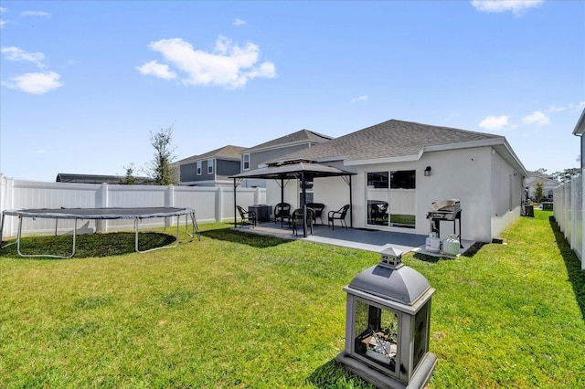 rear view of property with a gazebo, a yard, a patio, and a trampoline