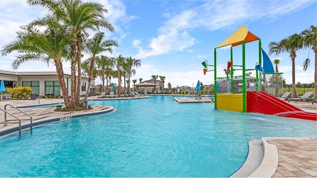 pool with a water play area, a patio, and fence