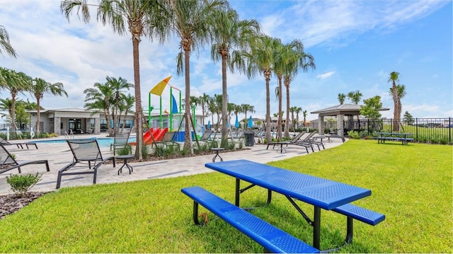 view of community featuring a swimming pool, a lawn, and fence