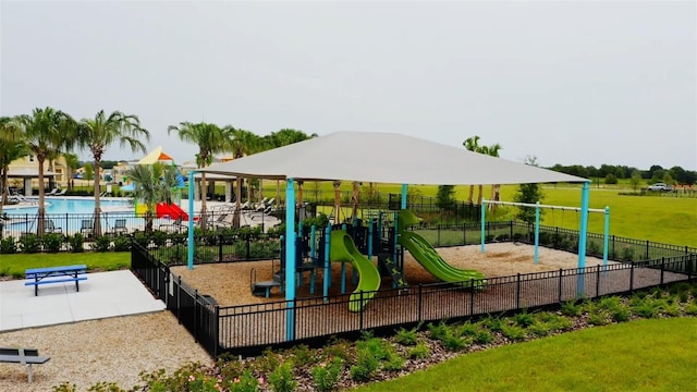 communal playground featuring a yard, a community pool, and fence