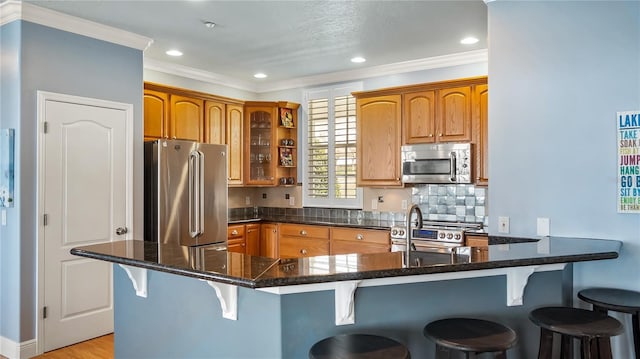 164 Nautica Mile Dr, Clermont, FL 34711 - kitchen with backsplash, glass insert cabinets, a kitchen bar, ornamental molding, and appliances with stainless steel finishes
