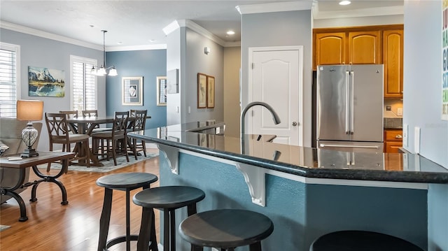 164 Nautica Mile Dr, Clermont, FL 34711 - kitchen with light wood-style floors, a breakfast bar area, brown cabinetry, high end refrigerator, and hanging light fixtures