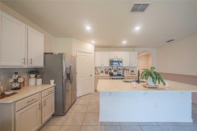 3719 Holly Grove Ln, Mount Dora, FL 32757 - kitchen featuring stainless steel appliances, decorative backsplash, arched walkways, a sink, and white cabinets