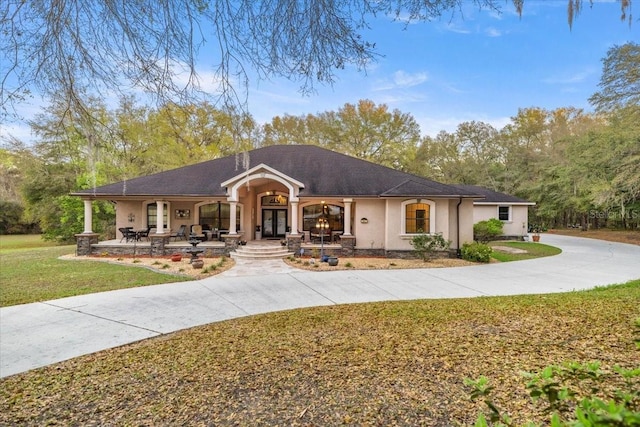 view of front of home featuring stucco siding, a porch, concrete driveway, and a front yard