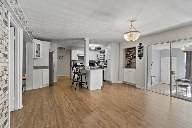 3058 SE 3rd Ave, Ocala, FL 34471 - kitchen featuring a center island, a breakfast bar, light wood-style flooring, appliances with stainless steel finishes, and white cabinets